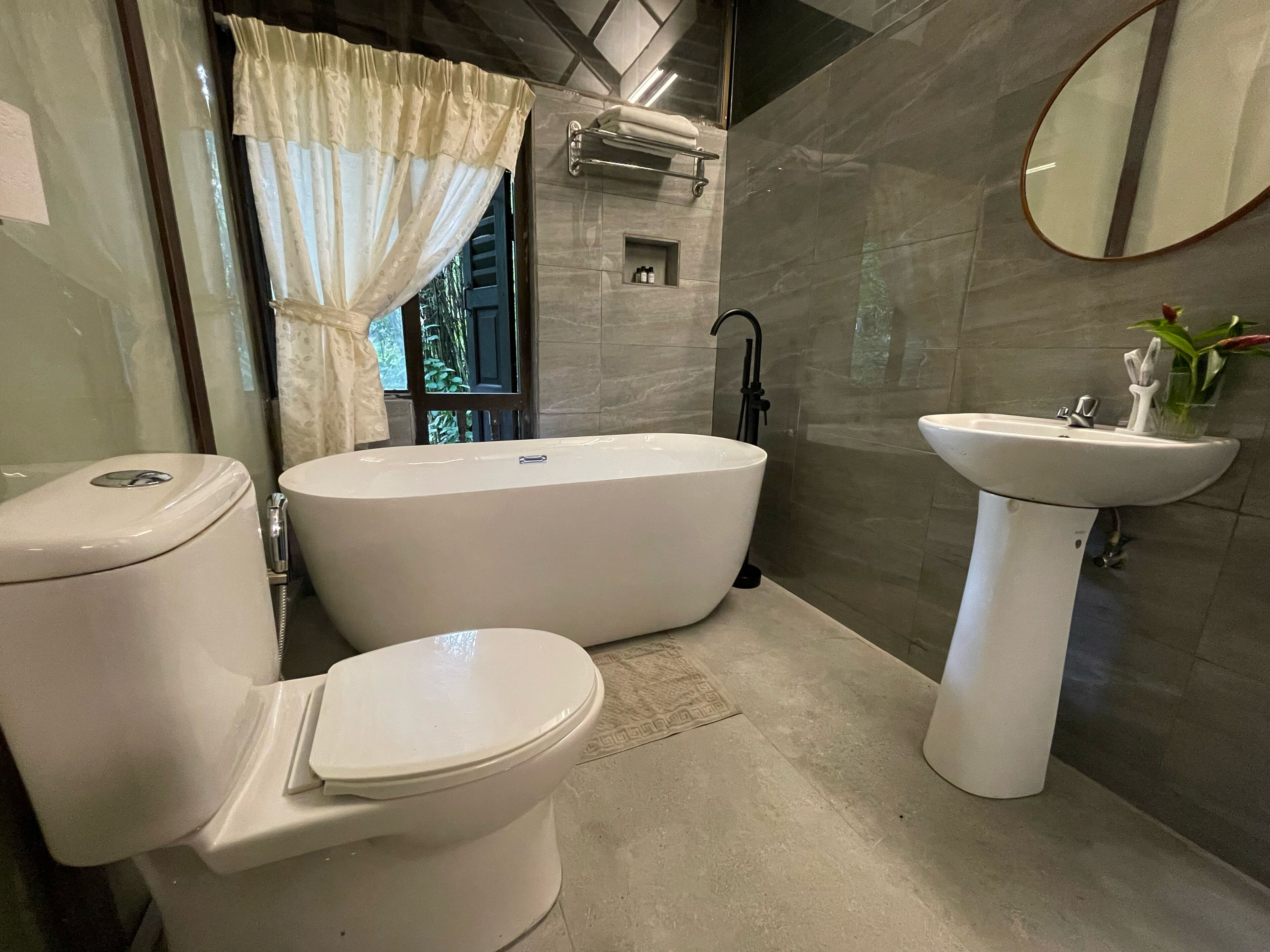 A bathroom with a toilet, a freestanding bathtub, and a pedestal sink.