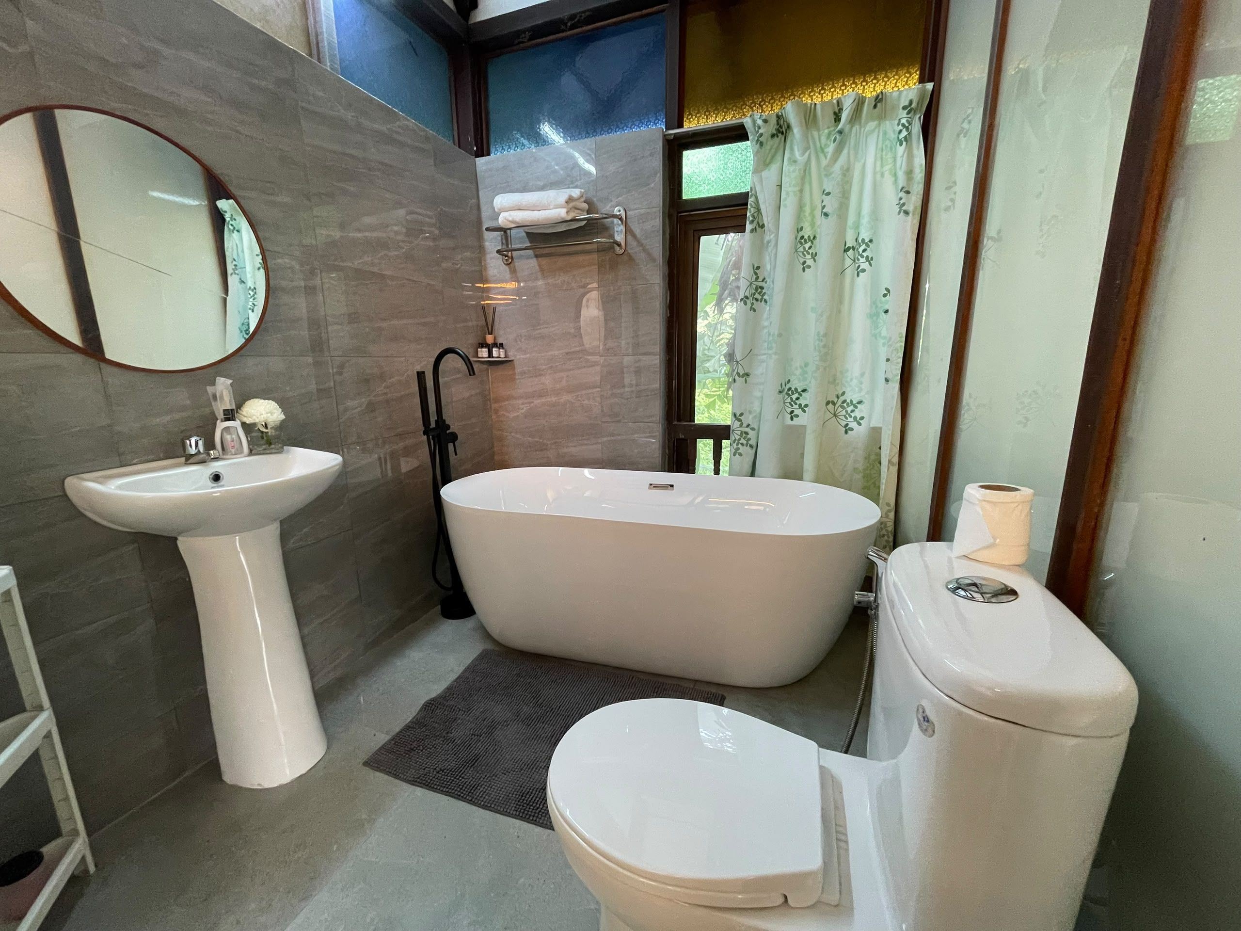 Un baño con una bañera independiente, un lavamanos sobre pedestal y un inodoro.