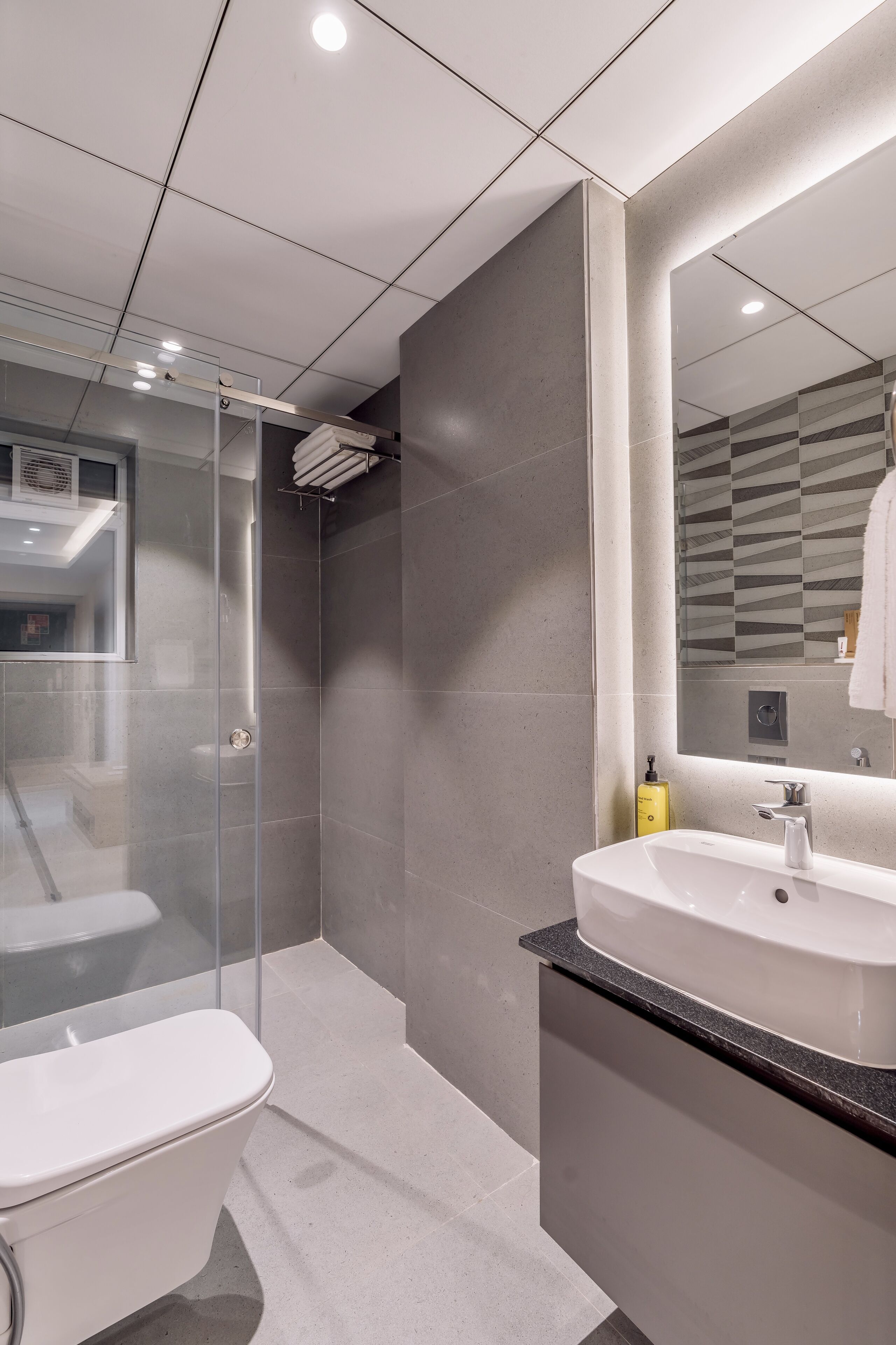 A modern bathroom with a glass-enclosed shower, a white sink, and a large mirror.