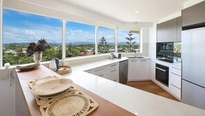 Una cocina moderna con amplios ventanales, vista a la ciudad y una isla de madera con elementos decorativos.