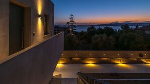 A modern building with a balcony overlooking a body of water and distant mountains. - Topos Suites (Kefalonia)
