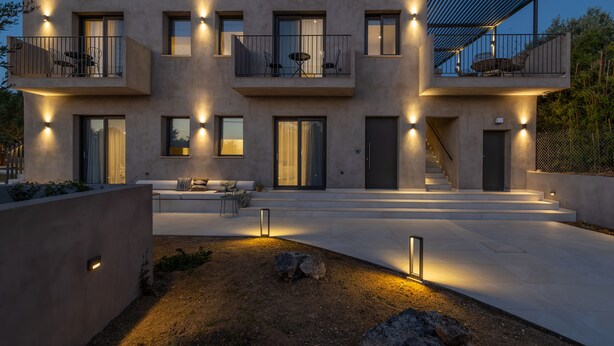 A modern multi-story building with balconies, large windows, and a well-lit entrance. - Topos Suites (Kefalonia)