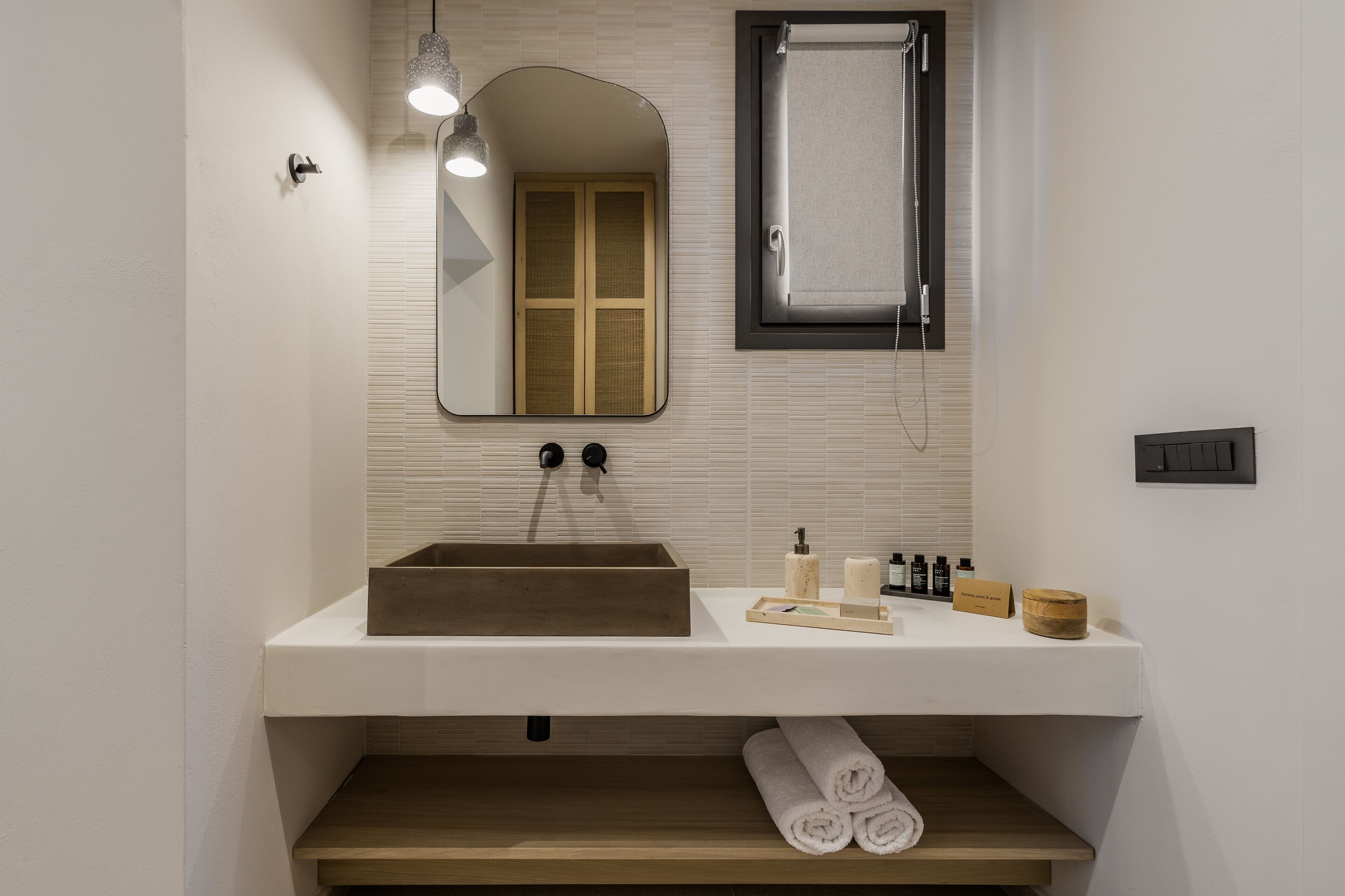 A modern bathroom with a wooden sink, a mirror, a towel rack, and a shelf with toiletries.