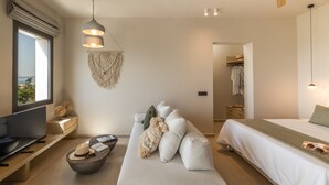 A modern bedroom with a bed, a sofa, a TV, and a desk. - Topos Suites (Kefalonia)