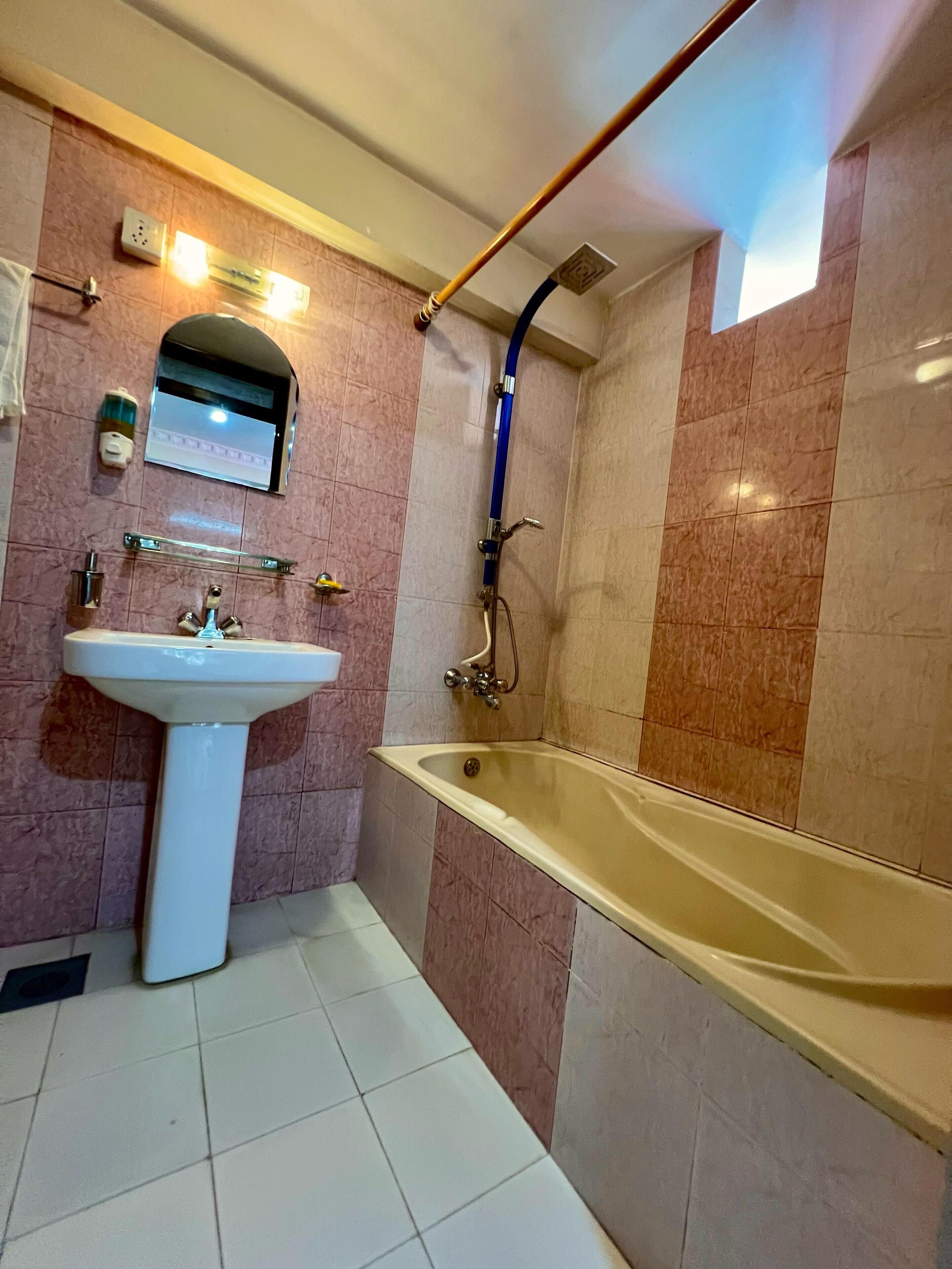A bathroom with a sink, mirror, and bathtub.