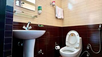 A bathroom with a pedestal sink, a toilet, a mirror, and a towel rack.