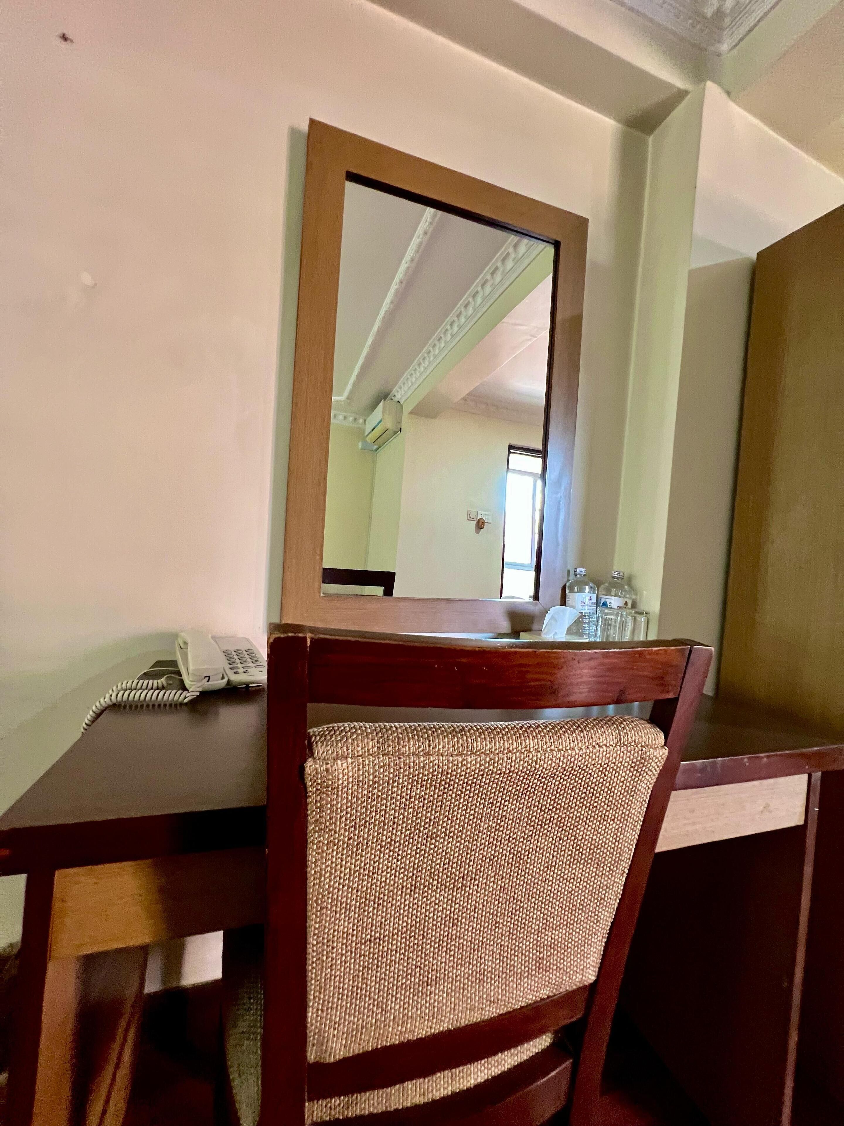 A wooden desk with a telephone and a mirror.
