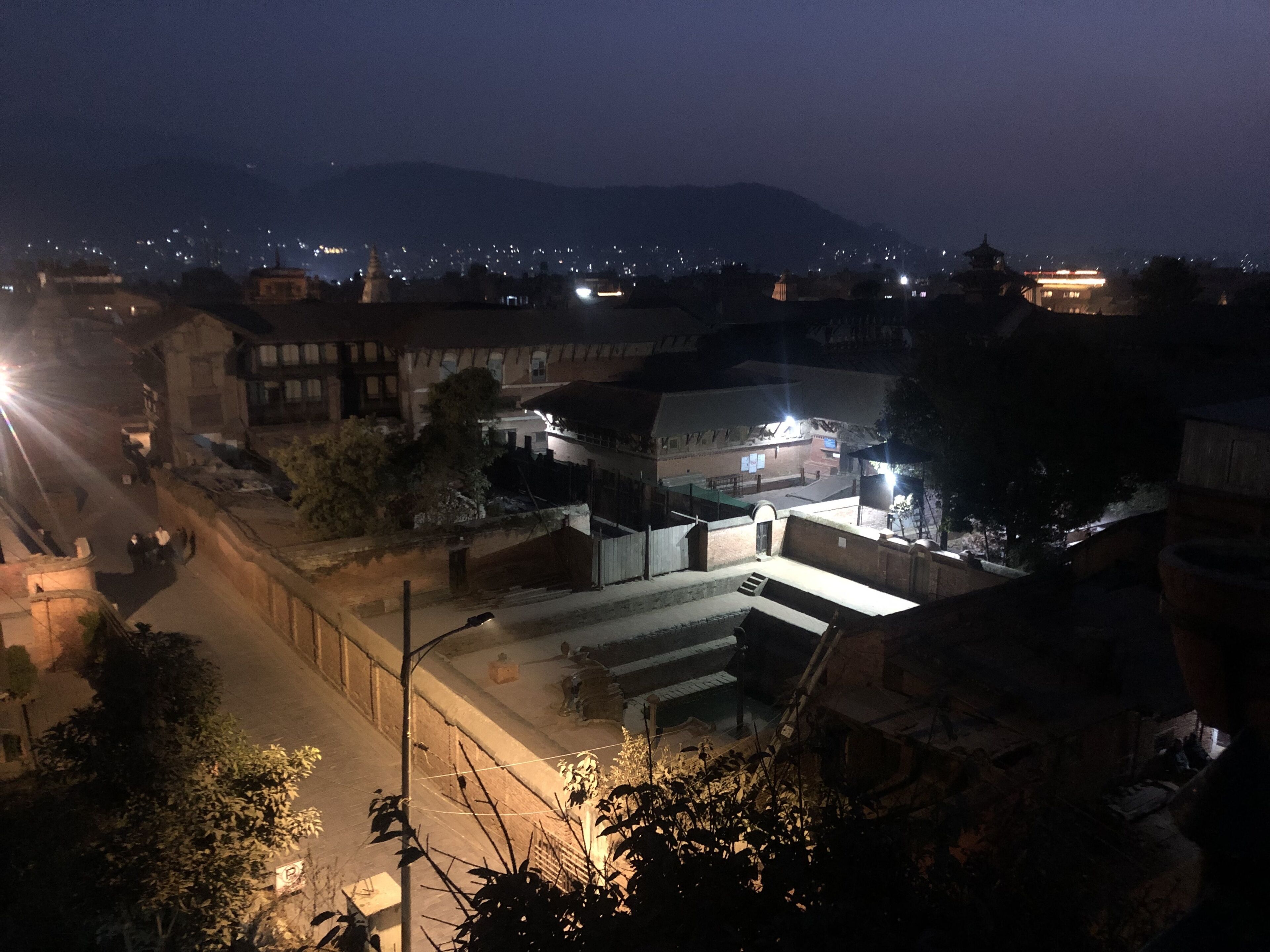 A nighttime view of a town with illuminated buildings and a street.