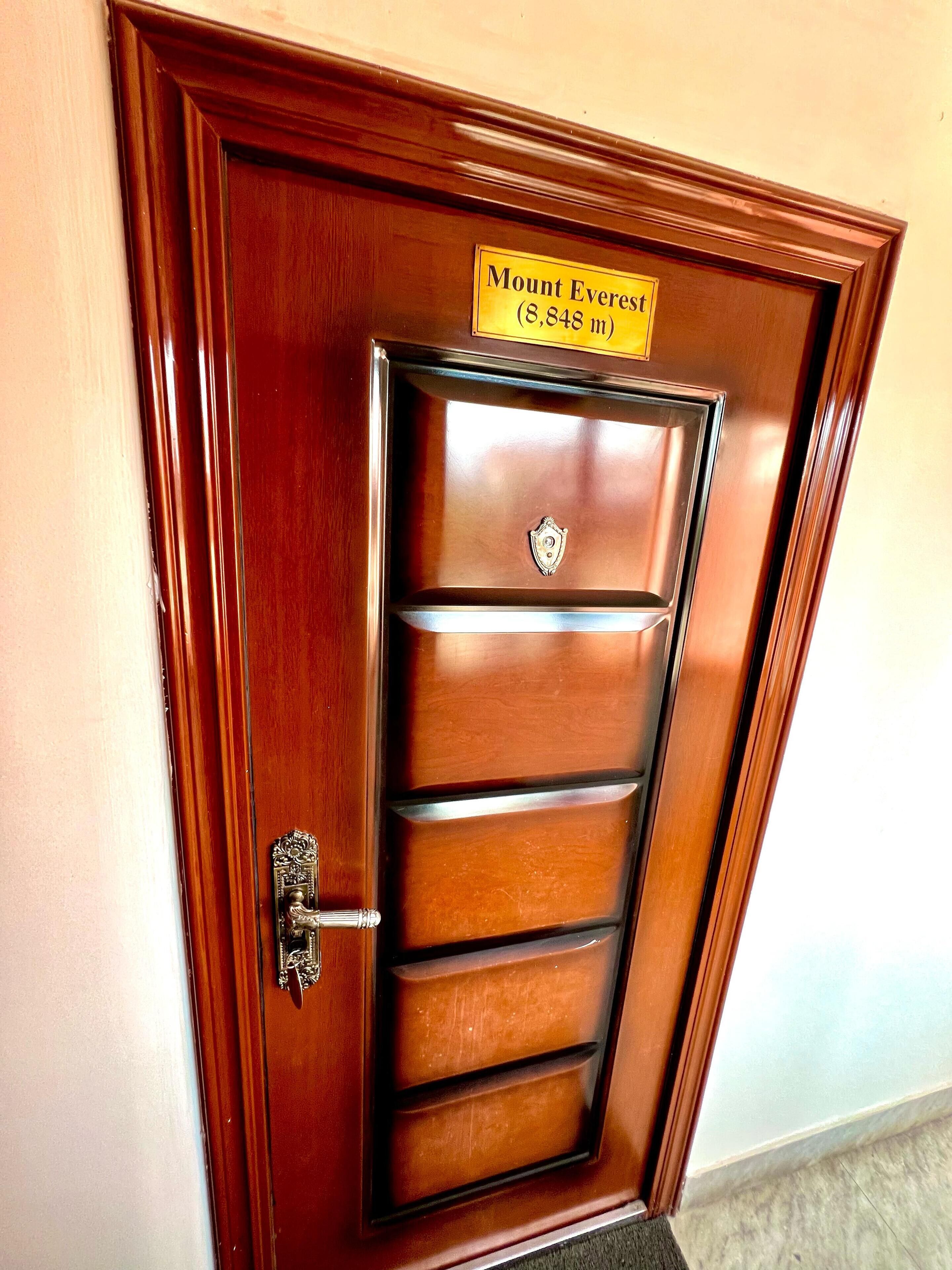 A wooden door with a sign reading "Mount Everest (8,848 m)" and a metal handle.