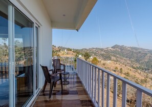 Enjoy breathtaking views of the surrounding mountains from this balcony, featuring a comfortable seating area with two chairs and a small table.