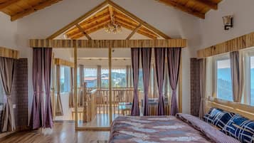 Un dormitorio con una cama grande, vigas de madera en el techo y un balcón con vistas.