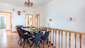 A dining area with a wooden railing, a chandelier, and a table set for six. - The Tahoma Stays (Dhari)