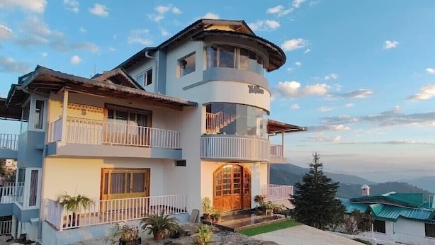 A multi-story building with a circular tower, balconies, and a large wooden door. - The Tahoma Stays (Dhari)