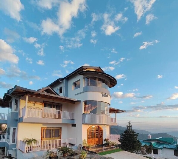 Stunning two-story building with a unique design, featuring a rounded corner and a balcony.
