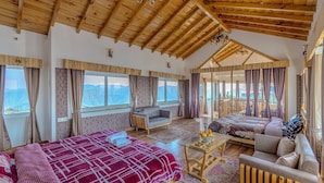 A spacious room with a high wooden ceiling, a large bed, a sofa, a small table, and a view of the mountains through large windows. - The Tahoma Stays (Dhari)