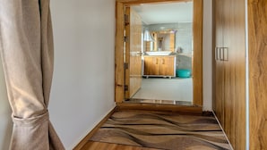 A narrow hallway with wooden flooring and a wooden door leading to a bathroom with a sink and cabinets. - The Tahoma Stays (Dhari)