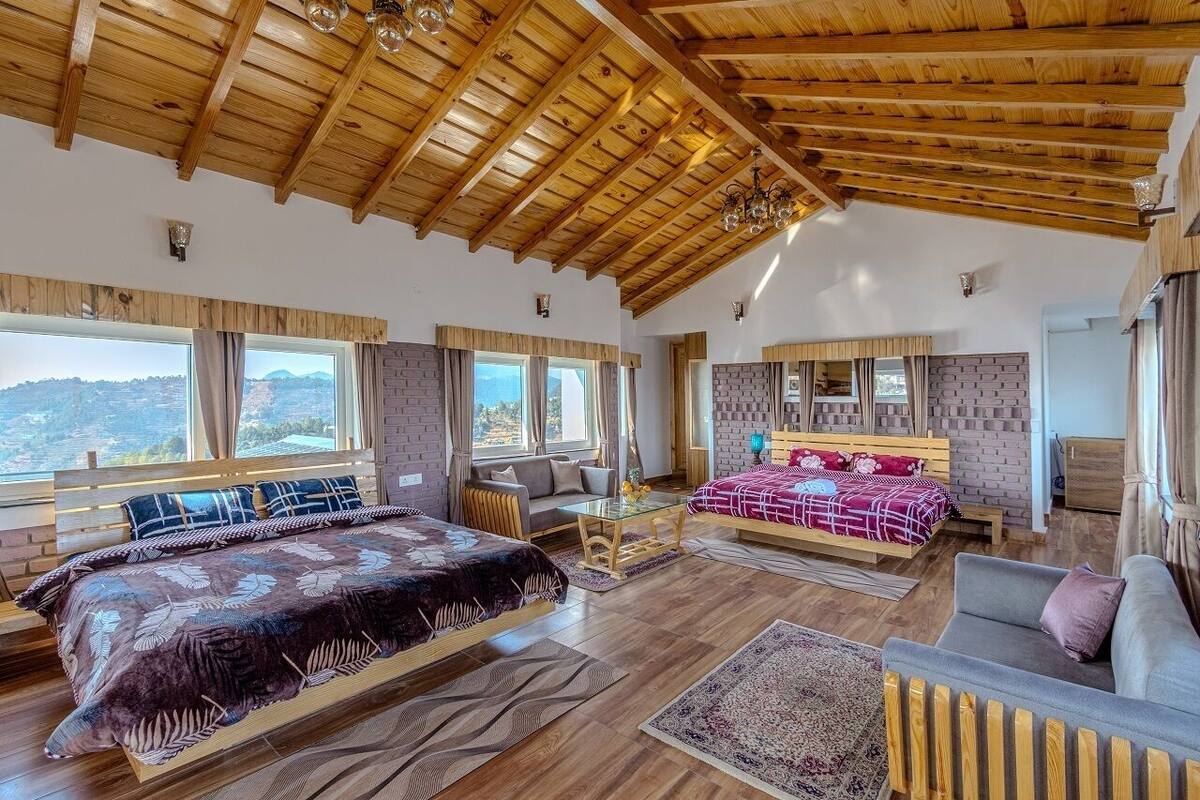 A spacious room with a wooden ceiling, large windows, a bed, a sofa, and a dining table.