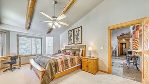 Une chambre à coucher comprenant un lit, un bureau, une chaise et un ventilateur de plafond.