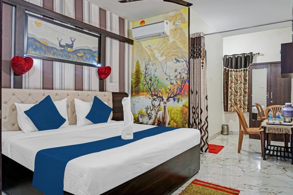 Un dormitorio con una cama grande, papel tapiz a rayas, un mural y una zona de comedor con una mesa y sillas.