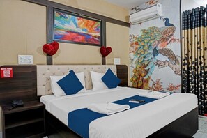 A hotel room with a large bed, a painting of a peacock, and a red heart decoration on the wall. - HOTEL VIRAJ (Pune)