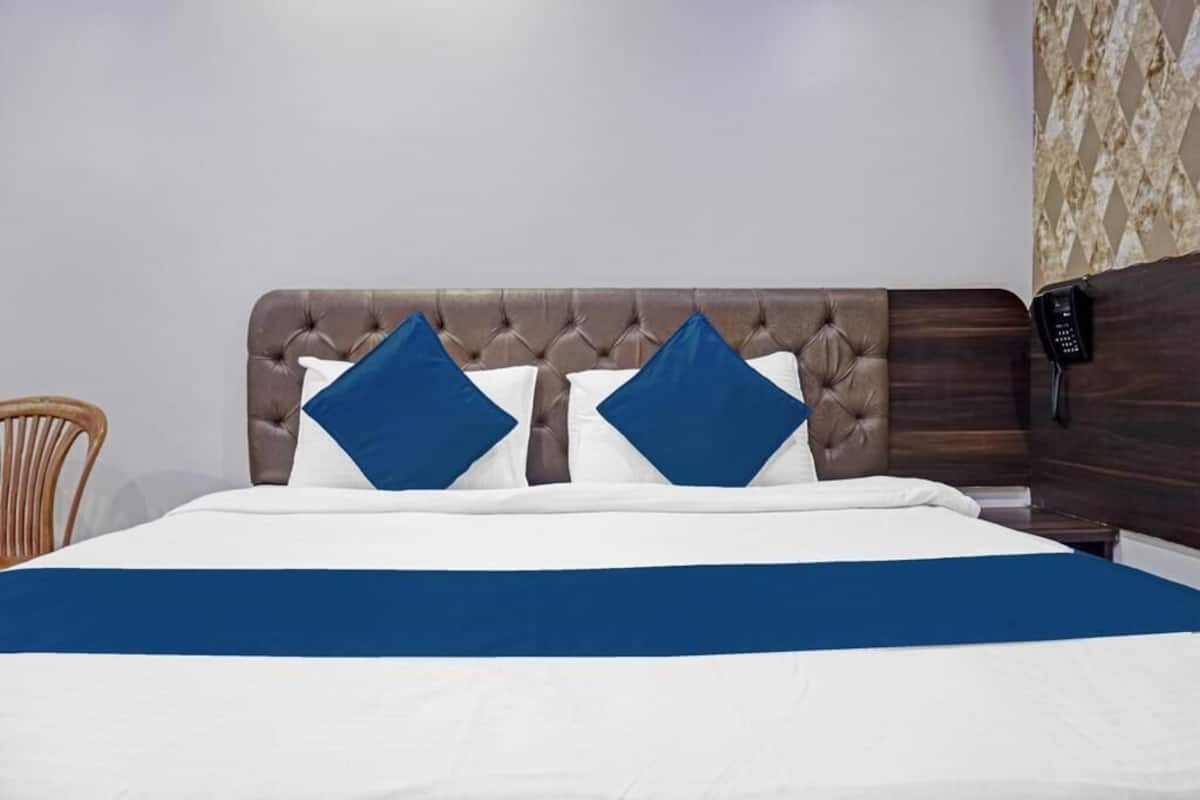 A bed with a tufted headboard, two pillows, and a blue bedspread.
