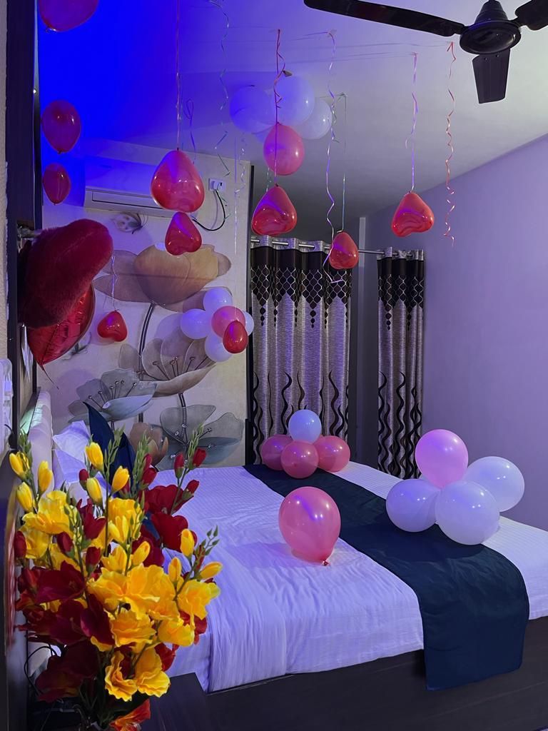 A room with a bed, decorative balloons, and a ceiling fan.