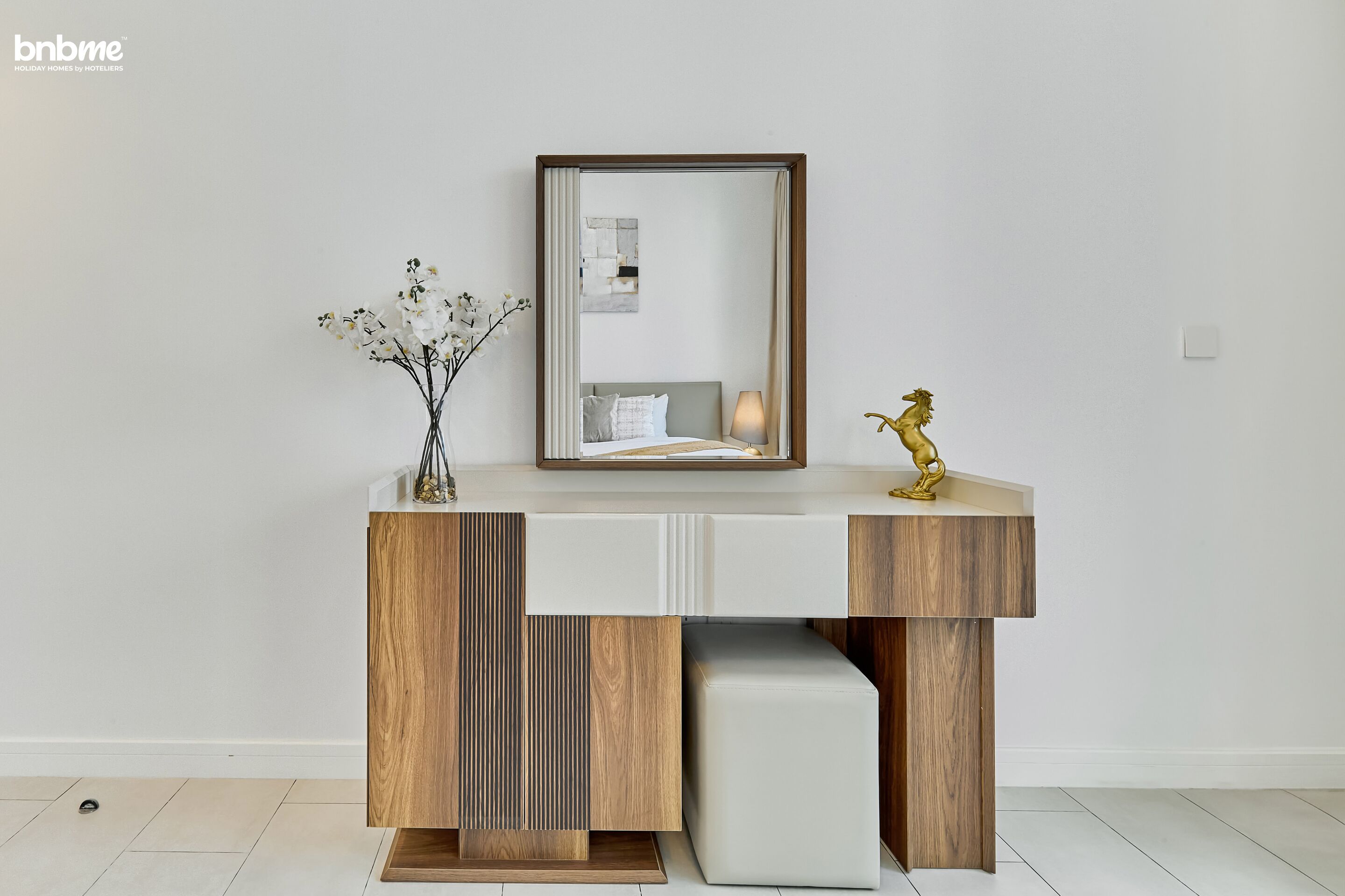 Une coiffeuse moderne agrémentée d’un miroir, d’un vase de fleurs et d’une statuette de cheval décorative.
