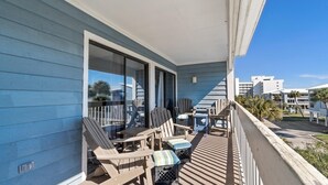 Un balcón con mobiliario exterior, incluyendo sillas y una mesa, con vistas a una zona residencial con palmeras y edificios.