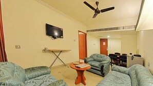 Un soggiorno con divani decorati, una TV, una ventola a soffitto e un tavolino.