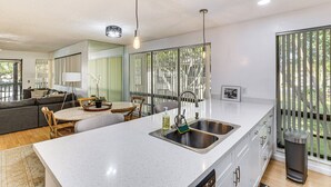 A modern kitchen with a large island, stainless steel sink, and pendant lighting. - Condo in PGA National Resort w/ Pool & Spa! (Palm Beach Gardens)