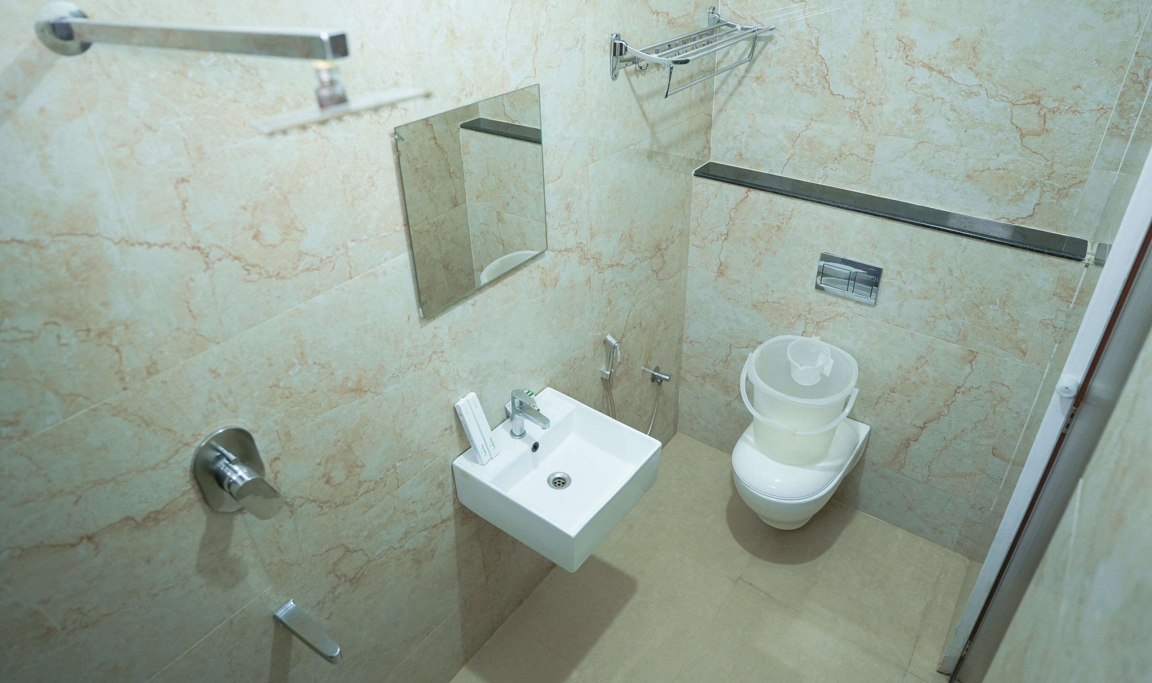 Une salle de bain moderne avec un lavabo blanc, des toilettes, un miroir et un espace douche.