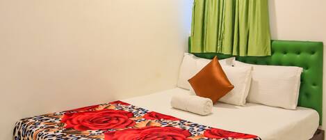 A bedroom with a bed, green curtains, a ceiling fan, and an air conditioning unit.