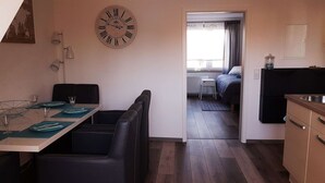Kompakti hotellihuone, jossa on ruokailutila, sänky ja pieni keittiönurkkaus.