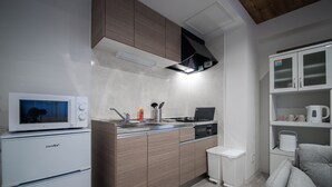 A compact kitchen with a microwave, sink, and modern cabinetry. - Astoria105 (Asahikawa)