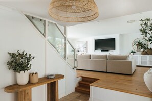 Een moderne woonkamer met een trap, een bank, een televisie en een plant.