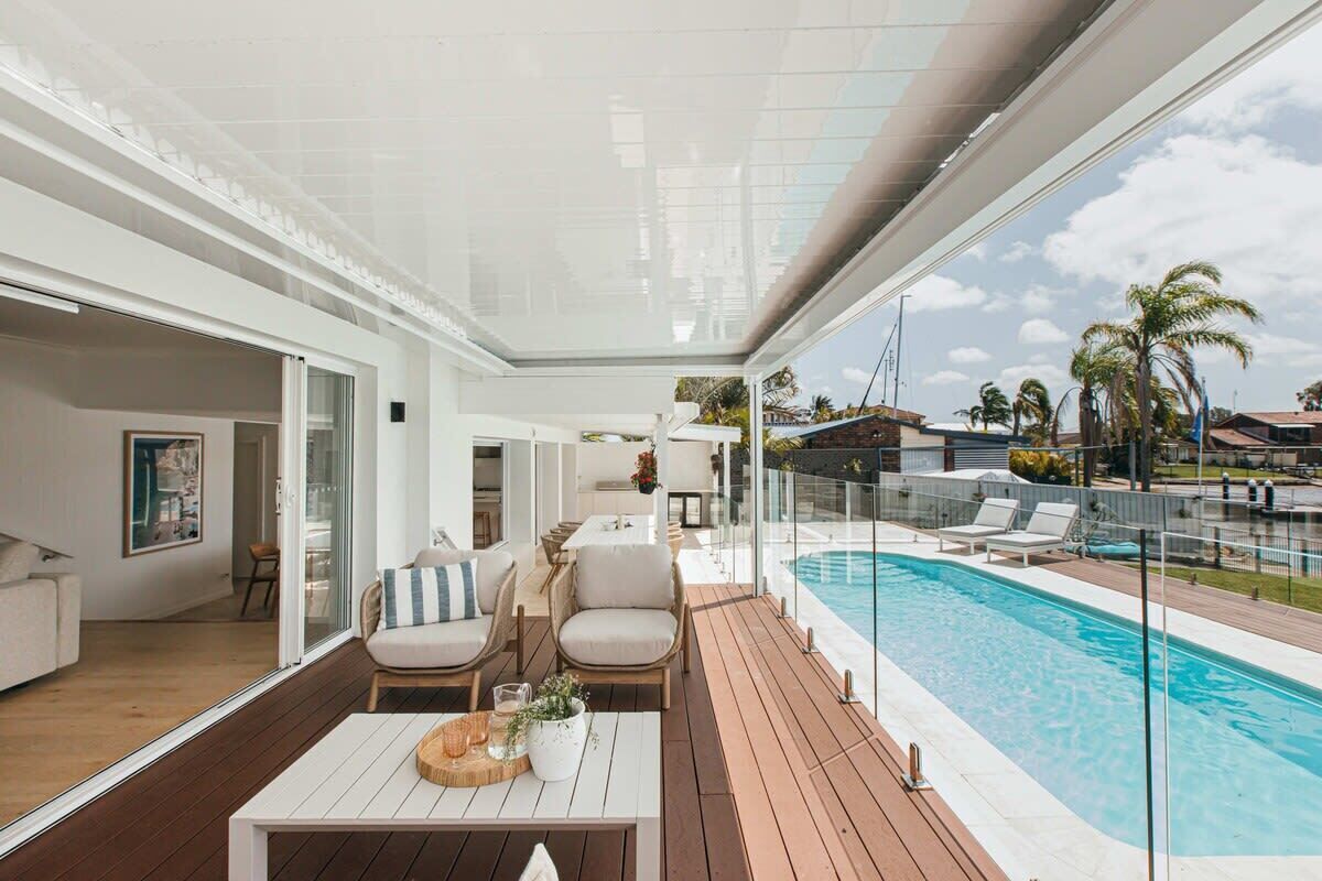 A modern outdoor living area with a pool, wooden deck, and comfortable seating.