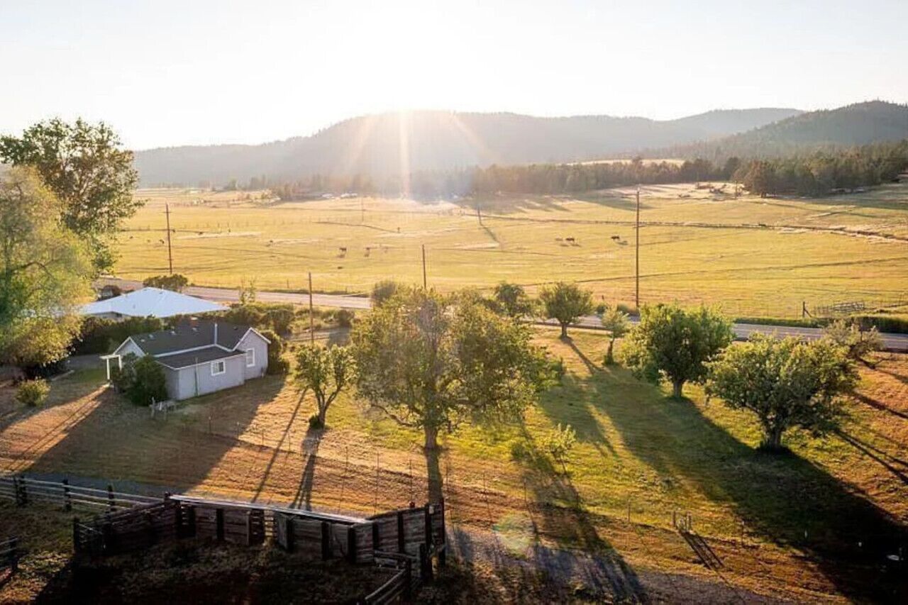 A rural landscape with a house, open fields, and a fence.