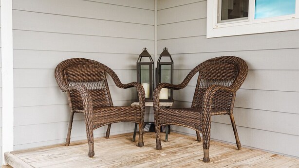 Un coin salon avec des fauteuils en osier et une table, une lanterne et une fenêtre.