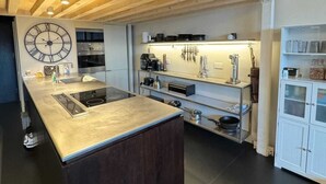 Una cocina moderna con una isla central, electrodomésticos integrados y un reloj de pared grande.