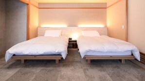 A bedroom with two single beds, a nightstand, and a wall-mounted light fixture. - Hokuryuko Hotel North Nagano (Iiyama)