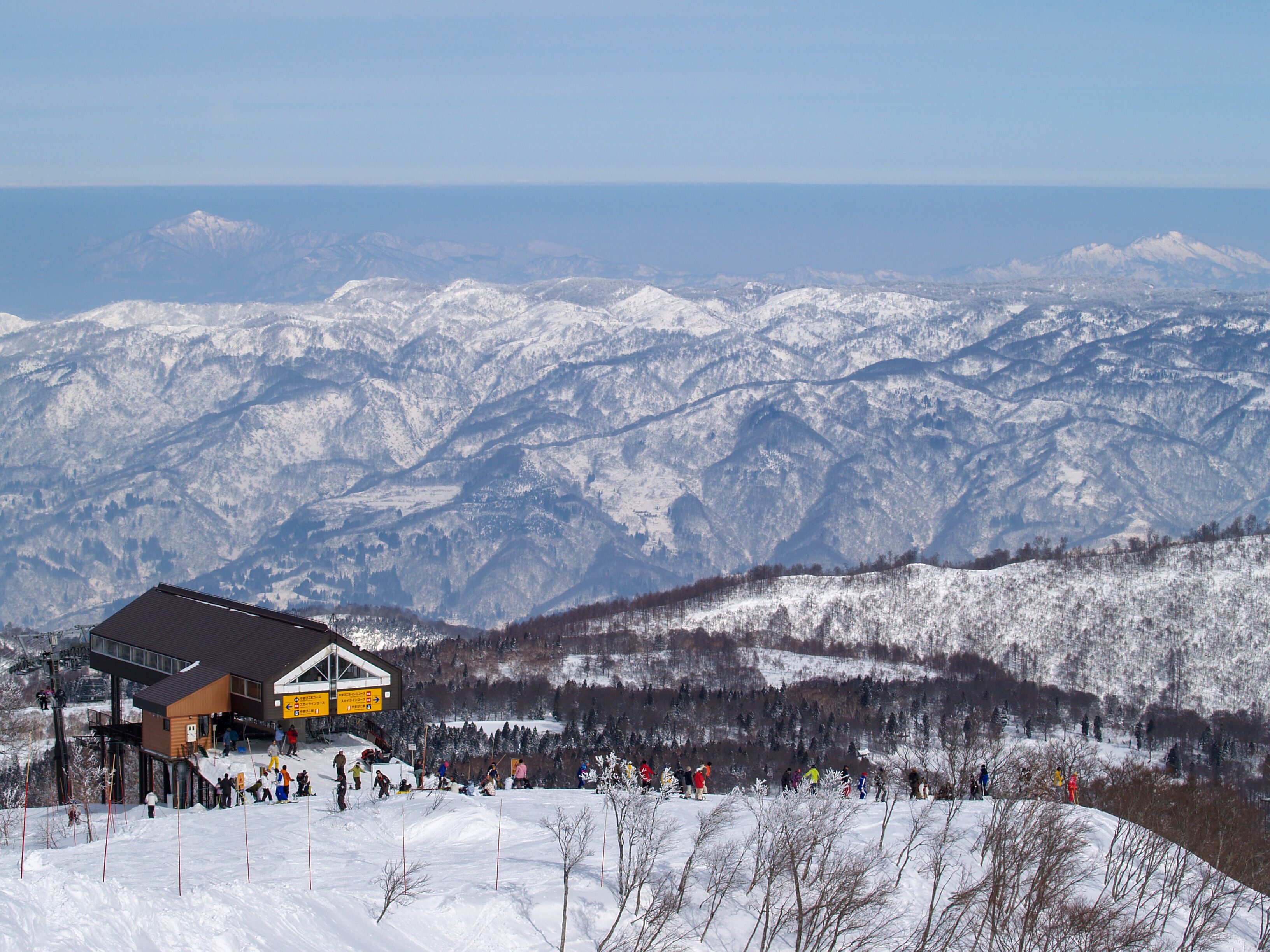 A ski resort with a building and a snowy mountain backdrop.