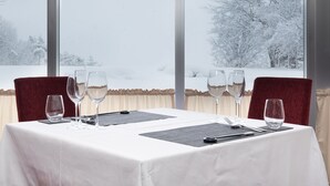A table set for dining with a view of snow-covered trees through large windows. - Hokuryuko Hotel North Nagano (Iiyama)