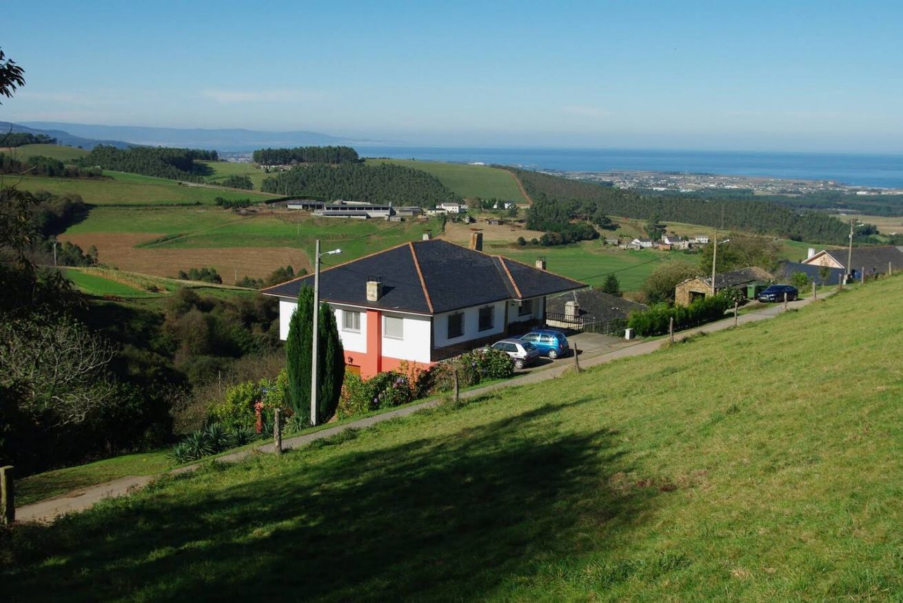 Une maison avec un toit en pente, une allée et une voiture garée devant.