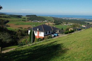 Une maison avec un toit en pente, une allée et une voiture garée devant.