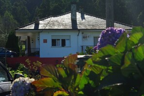 A single-story building with a sloped roof, a visible chimney, and a small balcony. - 30A01 Apartamentos rurales La Brañela (Castropol)