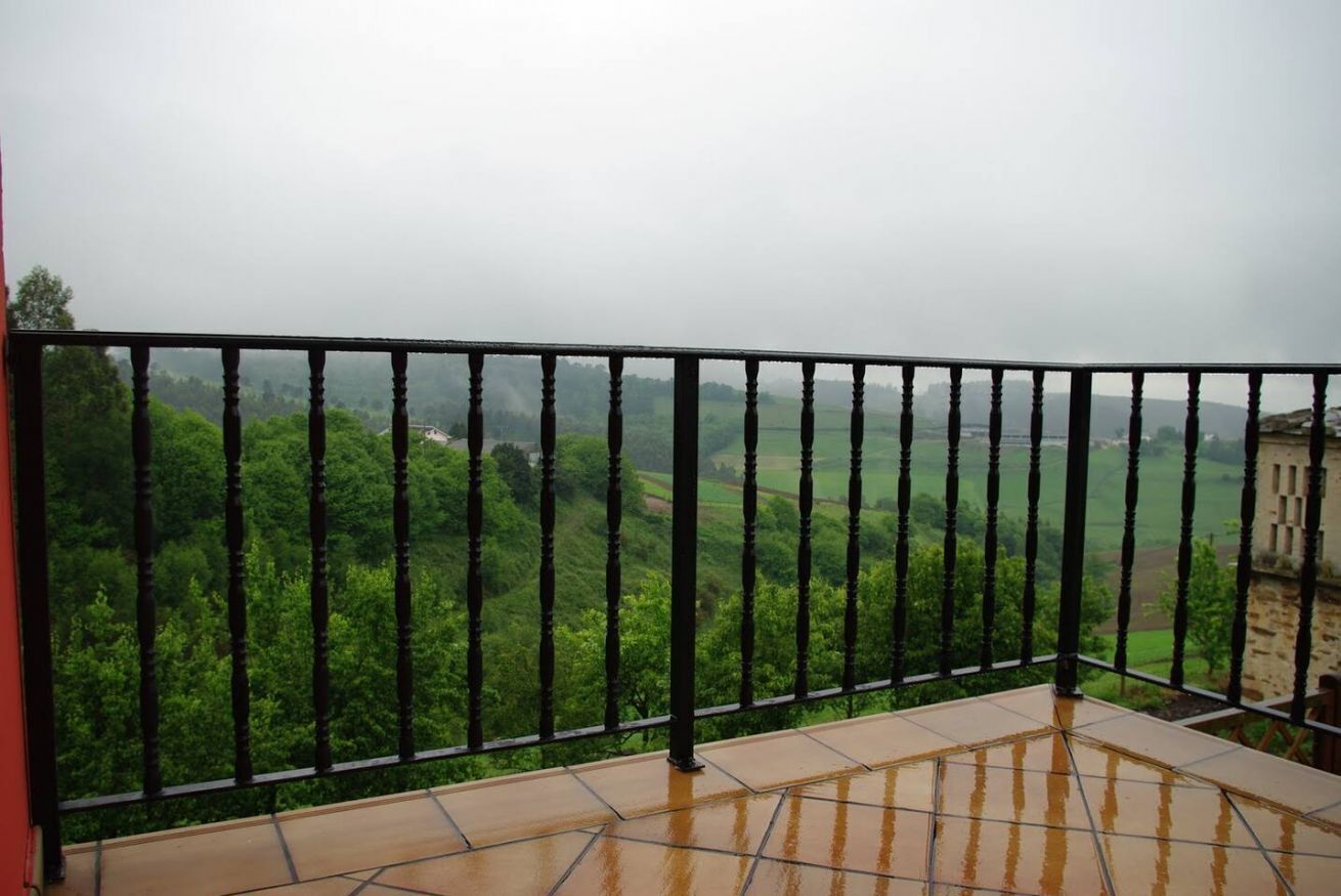 A balcony with a view of a green landscape.