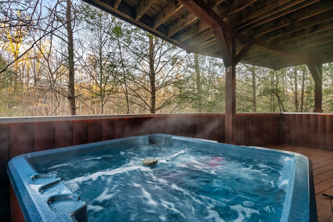 Jacuzzi con terraza de madera y vista a árboles.