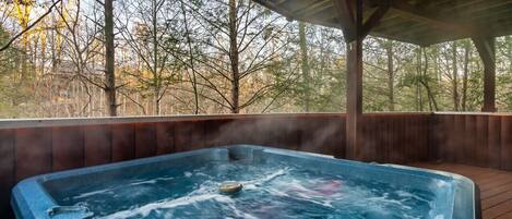 Jacuzzi con terraza de madera y vista a árboles.