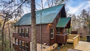 Een chalet met een metalen dak, houten terras en een klein terras.