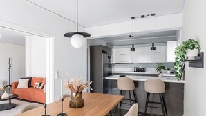 A modern kitchen with white cabinets, a black countertop, and a hanging light fixture. - Upscale 3BR Apartment in Chalandri (Chalandri)